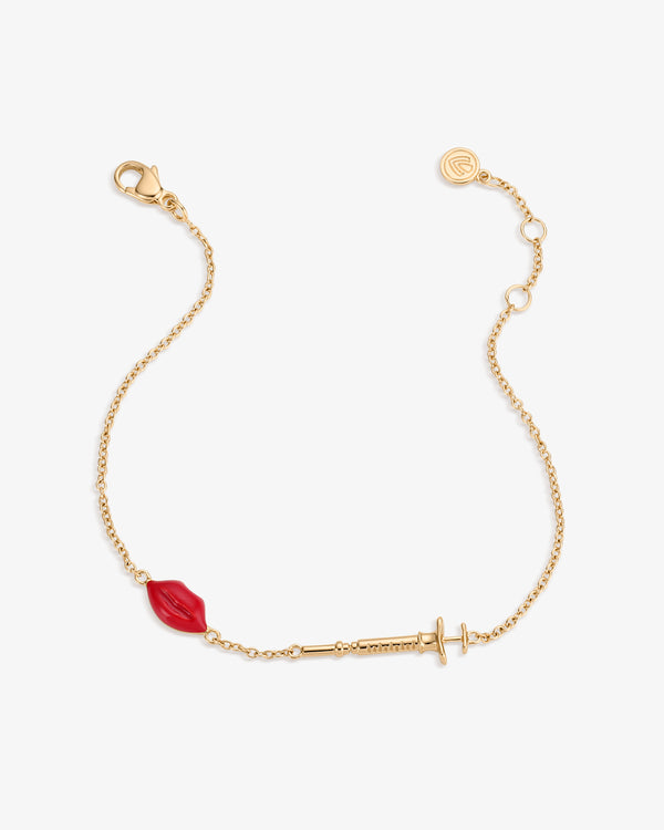 Gold bracelet with a red enameled lips charm and filler syringe pendant on a white background