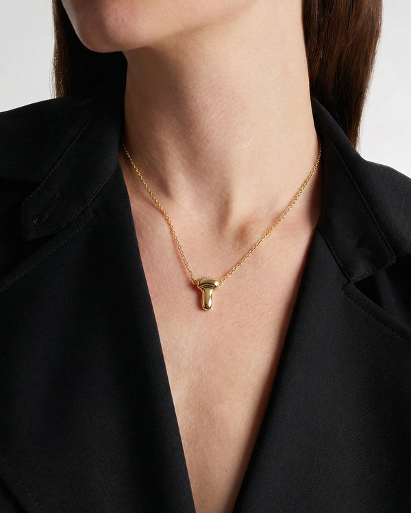 Gold necklace with an ultrasound probe pendant worn by a person styling a black blazer